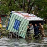 TOPSHOT - Homens coletam destroços em uma rua inundada depois que o Super Tufão Yagi atingiu Hai Phong, em 8 de setembro de 2024. O Super Tufão Yagi arranca milhares de árvores, varre navios e barcos para o mar e arranca telhados de casas no norte do Vietnã, depois de deixar um rastro de destruição no sul da China e nas Filipinas. (Foto de Nhac NGUYEN/AFP)