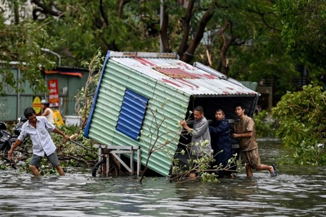 TOPSHOT - Homens coletam destroços em uma rua inundada depois que o Super Tufão Yagi atingiu Hai Phong, em 8 de setembro de 2024. O Super Tufão Yagi arranca milhares de árvores, varre navios e barcos para o mar e arranca telhados de casas no norte do Vietnã, depois de deixar um rastro de destruição no sul da China e nas Filipinas. (Foto de Nhac NGUYEN/AFP)