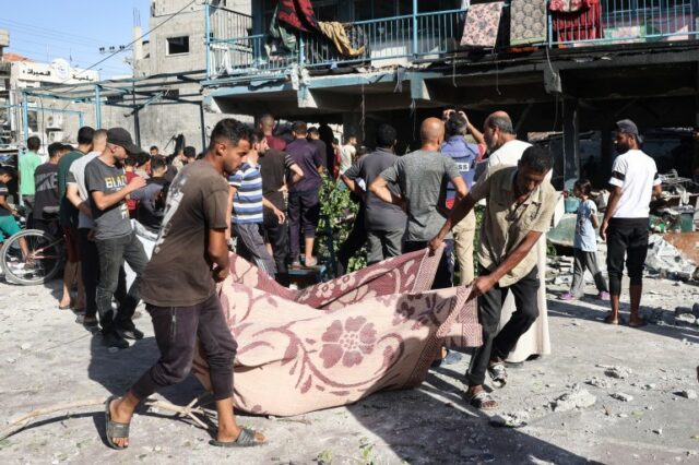 Pessoas usam um cobertor para transportar uma vítima depois que um ataque aéreo israelense atingiu uma escola em Nuseirat, no centro da Faixa de Gaza