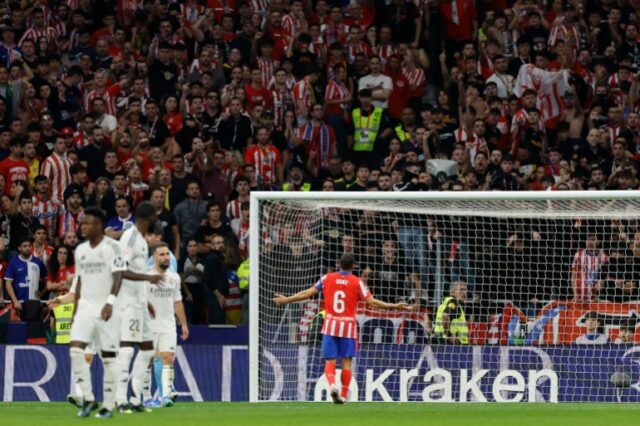 O meio-campista espanhol #06 Koke, do Atlético de Madrid, pede aos torcedores que parem de enviar itens para o campo depois que o zagueiro brasileiro #03 Eder Militão marcou o primeiro gol de seu time durante a partida de futebol da liga espanhola entre Club Atlético de Madrid e Real Madrid CF, no estádio Metropolitano, em Madrid em 29 de setembro de 2024. (Foto de OSCAR DEL POZO / AFP)