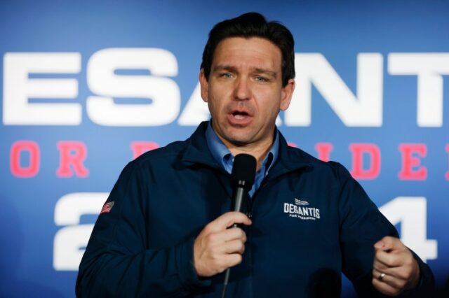 O governador Ron DeSantis fala ao microfone em frente a uma tela que mostra o logotipo de sua campanha presidencial.