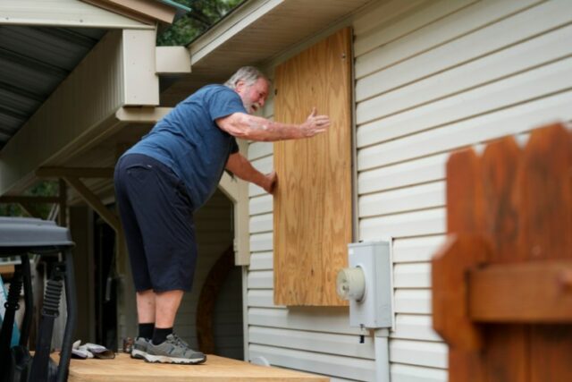 Um homem fecha as janelas de sua casa com tábuas antes da tempestade tropical Helene, que deverá atingir a costa como um furacão, em Ochlockonee Bay, Flórida, quarta-feira, setembro. 25 de outubro de 2024. (Gerald Herbert/AP)