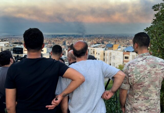 Cidadãos libaneses observam a fumaça subir dos ataques aéreos israelenses nos subúrbios ao sul de Beirute, Líbano, sábado, 28 de setembro de 2024. (AP Photo/Hussein Malla)