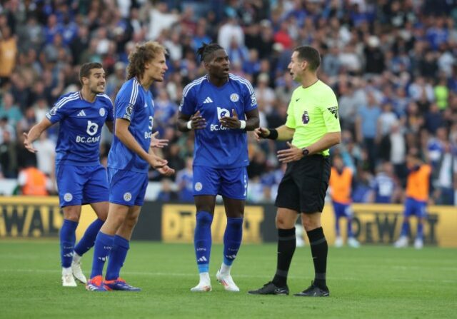 O árbitro David Coote reage a Wout Faes (à esquerda) e Caleb Okoli do Leicester City durante a partida da Premier League entre Leicester City FC e Aston Villa FC