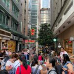 Mulheres reuniram-se numa rua pedonal no Distrito Central de Hong Kong. Existem edifícios altos em ambos os lados.