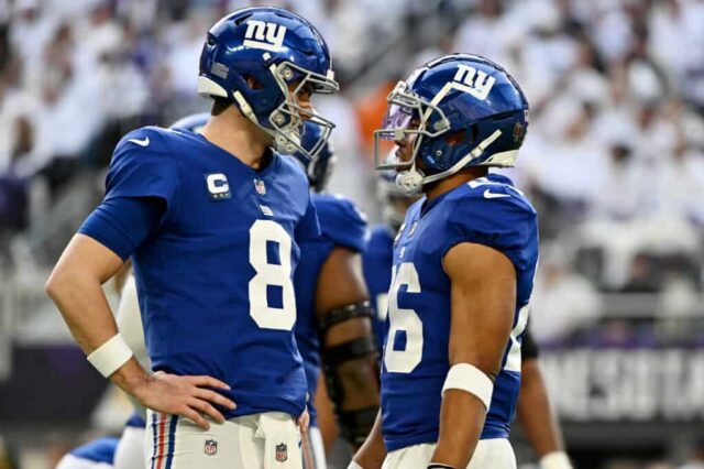 MINNEAPOLIS, MINNESOTA - 24 DE DEZEMBRO: Daniel Jones #8 e Saquon Barkley #26 do New York Giants falam em campo durante a primeira metade do jogo contra o Minnesota Vikings no US Bank Stadium em 24 de dezembro de 2022 em Minneapolis, Minnesota. 