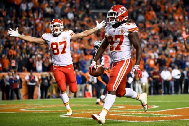 DENVER, CO - 1º DE OUTUBRO: O running back Kareem Hunt nº 27 do Kansas City Chiefs corre para a end zone com um touchdown no quarto período enquanto o tight end Travis Kelce nº 87 começa a comemorar no Broncos Stadium em Mile High em 1º de outubro de 2018 em Denver, Colorado.