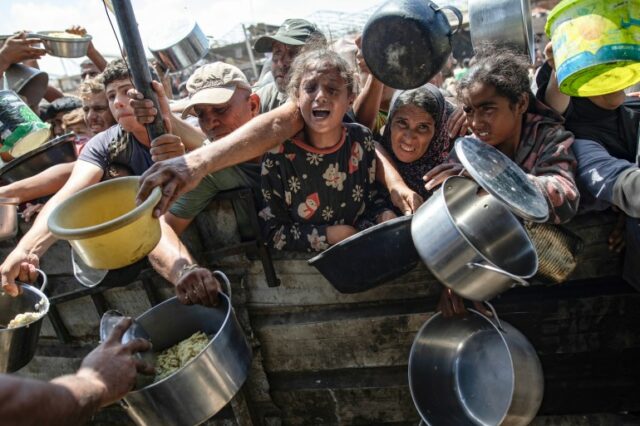 Palestinos deslocados internamente recebem alimentos doados por uma instituição de caridade, em Khan Younis