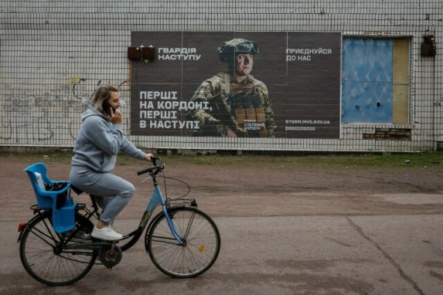 Um residente local anda de bicicleta perto de um anúncio de recrutamento para o exército ucraniano, em meio ao ataque da Rússia à Ucrânia, na vila de Hrushivka, região de Dnipropetrovsk, Ucrânia, 14 de junho de 2023. REUTERS/Alina Smutko