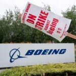 Uma placa de greve está pendurada em um poste perto de uma placa da Boeing em Renton, Washington, EUA