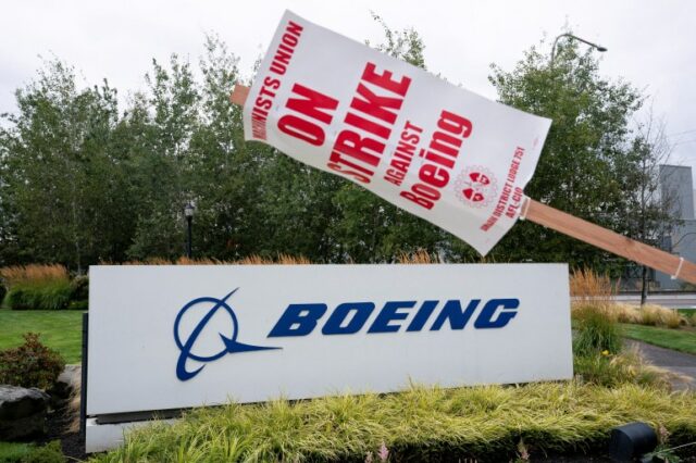 Uma placa de greve está pendurada em um poste perto de uma placa da Boeing em Renton, Washington, EUA