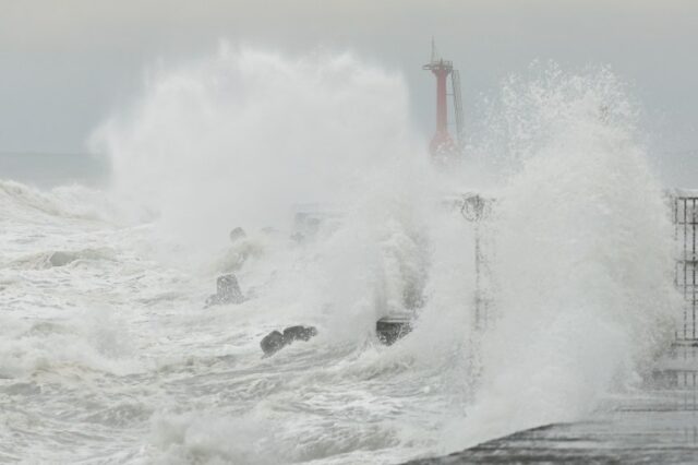 Ondas quebrando em um paredão em Khaosiung. Um posto de observação vermelho no final da parede pode ser visto através da água e da maresia