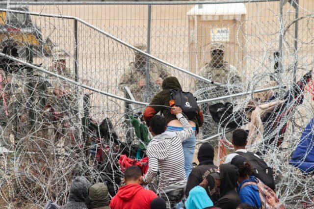 Um grupo de migrantes tenta cruzar uma cerca de arame farpado para chegar ao lado dos EUA, visto de Ciudad Juarez, México, em 20 de março.