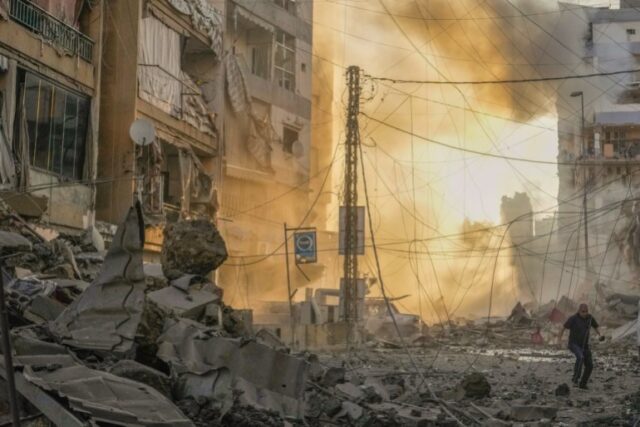 Um homem corre para se proteger enquanto uma fumaça sobe ao fundo após um ataque aéreo israelense em Dahiyeh, Beirute, Líbano, sexta-feira, 4 de outubro de 2024. (AP Photo/Hassan Ammar)