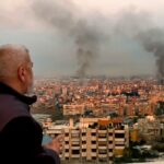 Um homem observa enquanto a fumaça sobe dos ataques aéreos israelenses em Dahiyeh, Beirute,