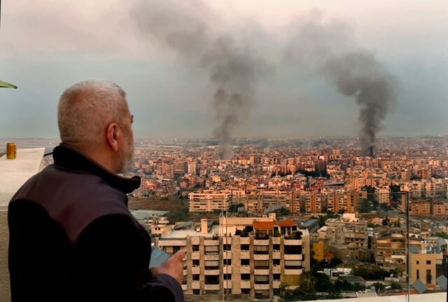 Um homem observa enquanto a fumaça sobe dos ataques aéreos israelenses em Dahiyeh, Beirute,