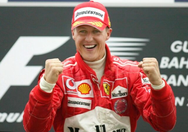 Michael Schumacher fotografado com um enorme sorriso e cerrando os punhos em comemoração enquanto usava equipamento da Ferrari