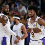 O guarda do Los Angeles Lakers, Bronny James (9), à direita, entra na quadra com o atacante do Los Angeles Lakers, LeBron James (23), durante a primeira metade de um jogo de basquete da pré-temporada da NBA