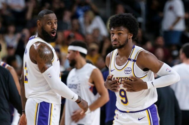 O guarda do Los Angeles Lakers, Bronny James (9), à direita, entra na quadra com o atacante do Los Angeles Lakers, LeBron James (23), durante a primeira metade de um jogo de basquete da pré-temporada da NBA