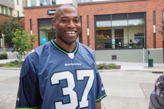 SEATTLE, WA - 25 DE SETEMBRO: A lenda do Seattle Seahawks, Shaun Alexander, entrega mantimentos aos fãs dos Seahawks para dar início ao apoio da American Express ao Blue Friday em 25 de setembro de 2015 em Seattle, Washington.