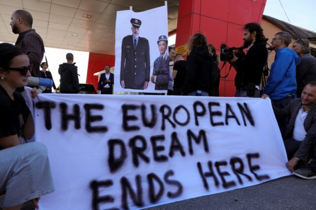 Um grupo de ativistas dos direitos civis se reúne em protesto, depois que o primeiro grupo de migrantes interceptados em águas italianas chegou ao porto de Shengjin, na Albânia, em 16 de outubro de 2024 (Adnan Beci/AFP)