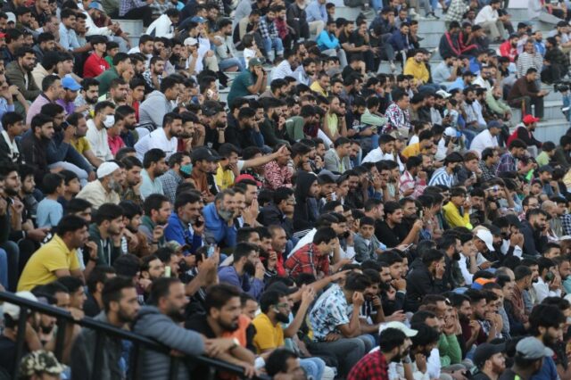 Pessoas assistindo à partida de críquete dentro do Estádio Bakshi, na principal cidade de Srinagar, onde milhares de torcedores se reuniram para assistir aos jogadores de críquete internacionais aposentados jogando em sua cidade natal. (Shuaib Bashir/Al Jazeera)